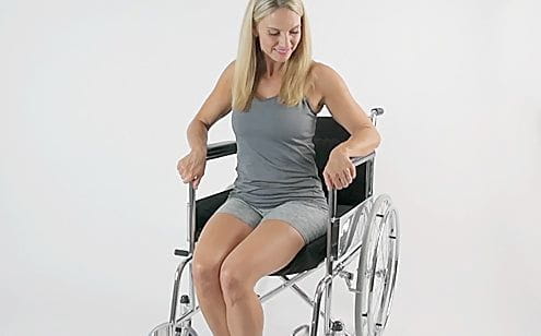 Middle age woman sitting in a wheel chair with cushion